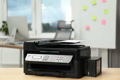 Photo of Modern printer with paper on wooden table in office