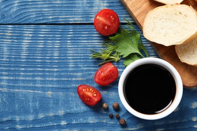 Balsamic vinegar, bread and other products on blue wooden table, flat lay. Space for text