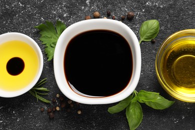 Photo of Balsamic vinegar, oil and other products on black textured table, flat lay