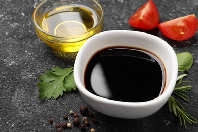 Photo of Balsamic vinegar, oil and other products on black textured table, closeup