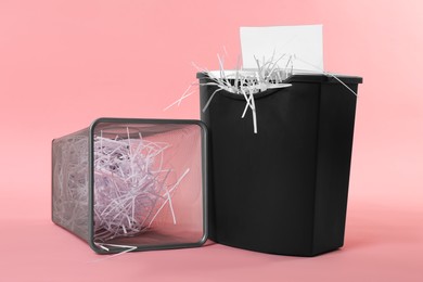 Photo of Shredder, metal basket and paper strips on pink background