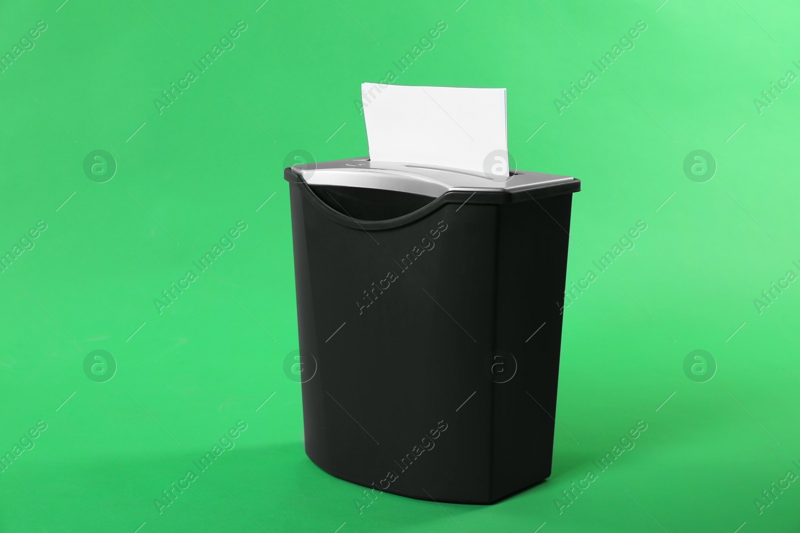 Photo of Shredder with sheet of paper on green background