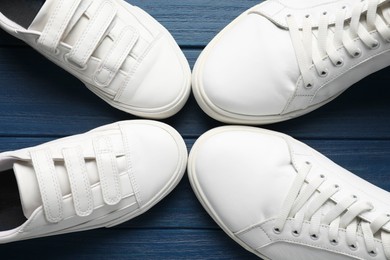 Photo of Big and small shoes on blue wooden table, top view