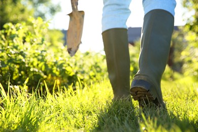 Farmer walking with shovel on sunny day, closeup