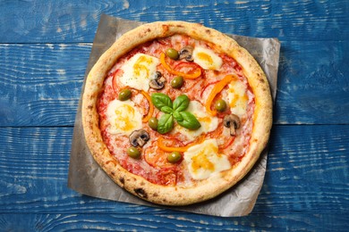 Photo of Delicious vegetarian pizza on blue wooden table, top view