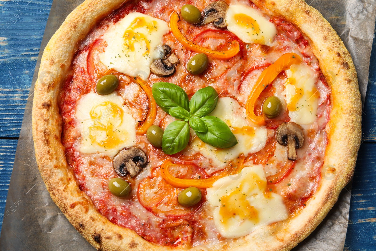 Photo of Delicious vegetarian pizza on blue wooden table, top view