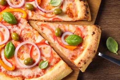 Photo of Cut delicious vegetarian pizza on wooden table, top view