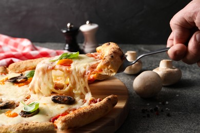 Photo of Man taking piece of delicious vegetarian pizza at grey table, closeup