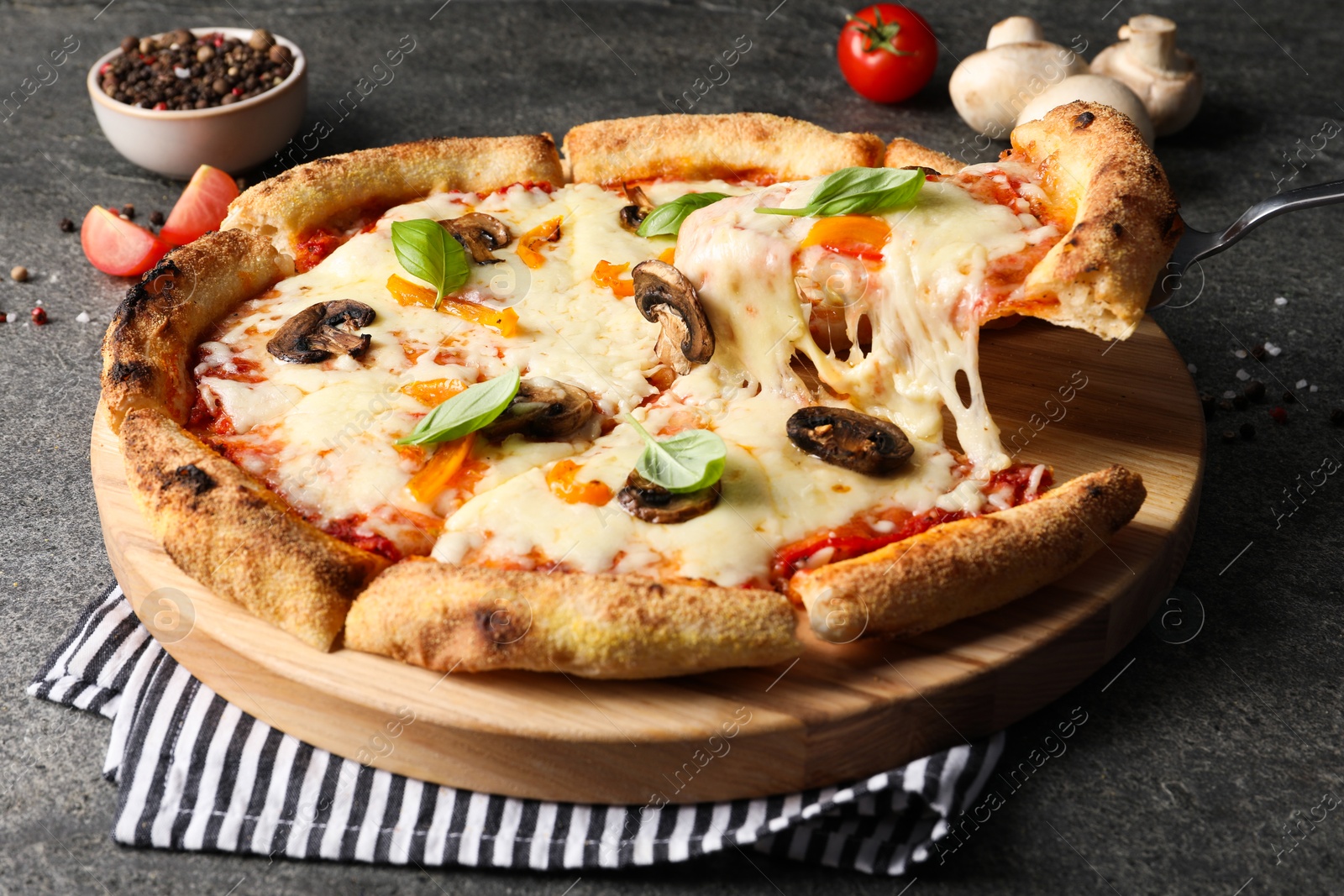 Photo of Taking piece of delicious vegetarian pizza at grey table, closeup