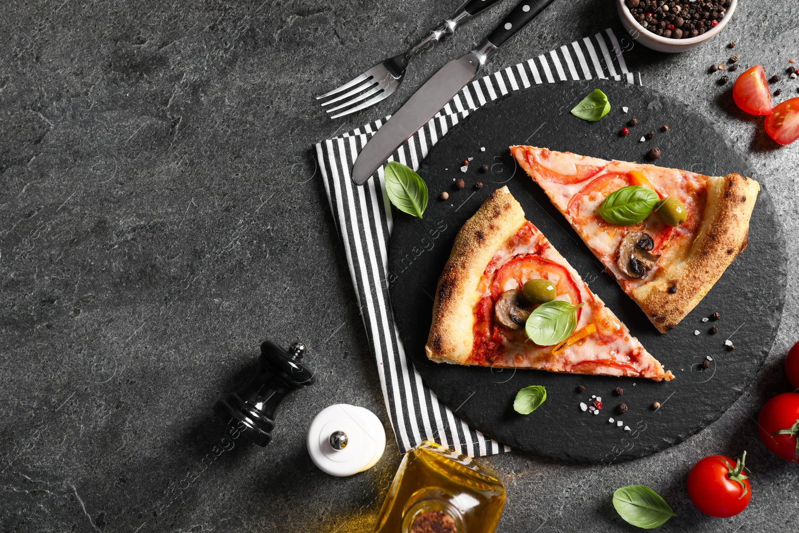 Photo of Cut delicious vegetarian pizza, cutlery and ingredients on grey table, top view. Space for text