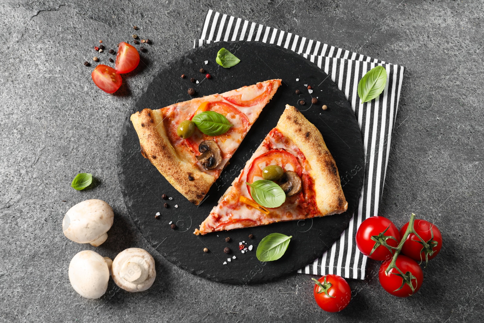 Photo of Cut delicious vegetarian pizza, spices, tomatoes and mushrooms on grey table, top view