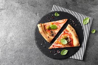 Photo of Cut delicious vegetarian pizza and spices on grey table, top view. Space for text