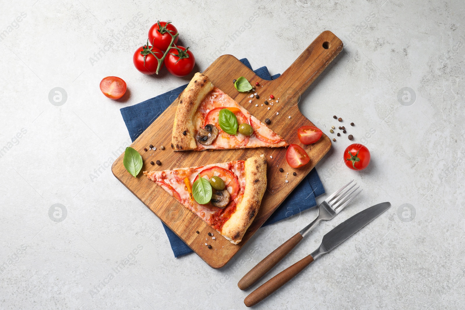 Photo of Cut delicious vegetarian pizza, cutlery and ingredients on light grey table, top view