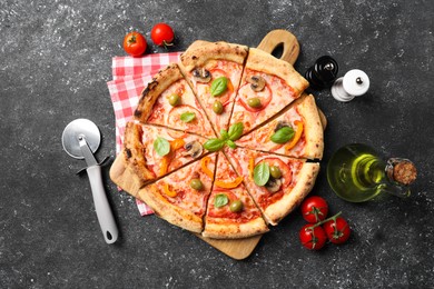 Photo of Cut delicious vegetarian pizza, cutter, oil, tomatoes and spices on grey table, top view