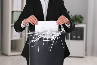 Photo of Woman destroying sheet of paper with shredder in office, closeup