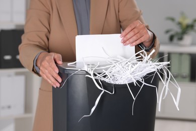 Photo of Woman destroying paper with shredder in office, closeup