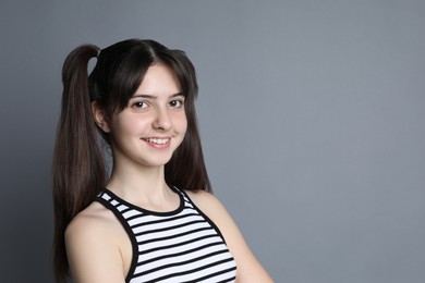 Portrait of smiling teenage girl on grey background. Space for text