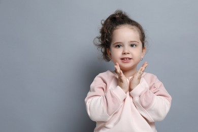 Photo of Adorable child. Portrait of smiling girl on grey background. Space for text