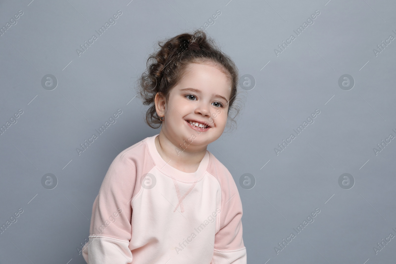 Photo of Adorable child. Portrait of smiling girl on grey background