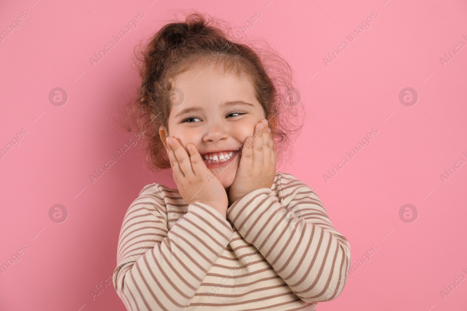 Photo of Adorable child. Portrait of happy girl on pink background