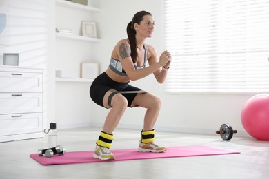 Woman with ankle weights and elastic band training indoors