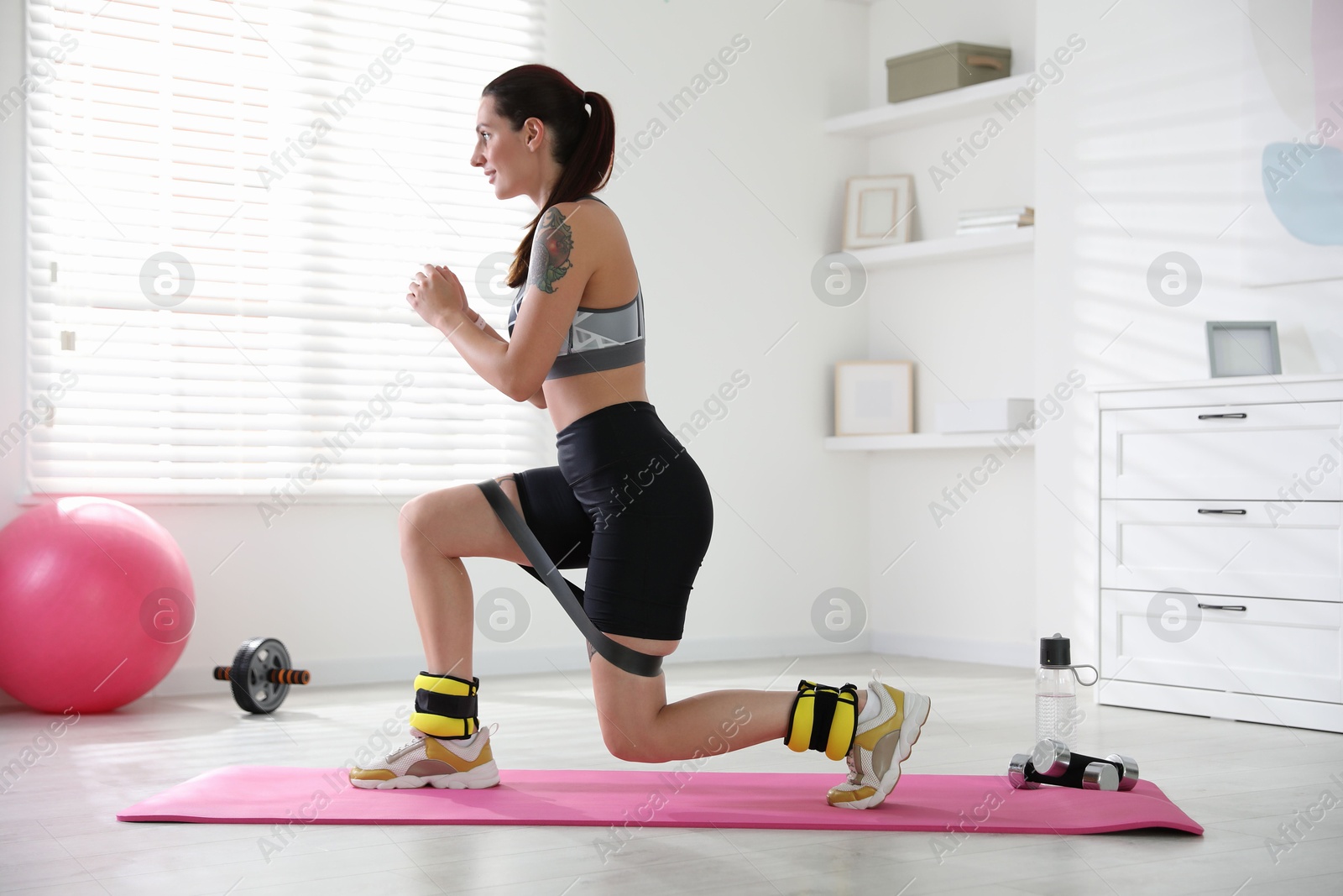 Photo of Woman with ankle weights and elastic band training indoors