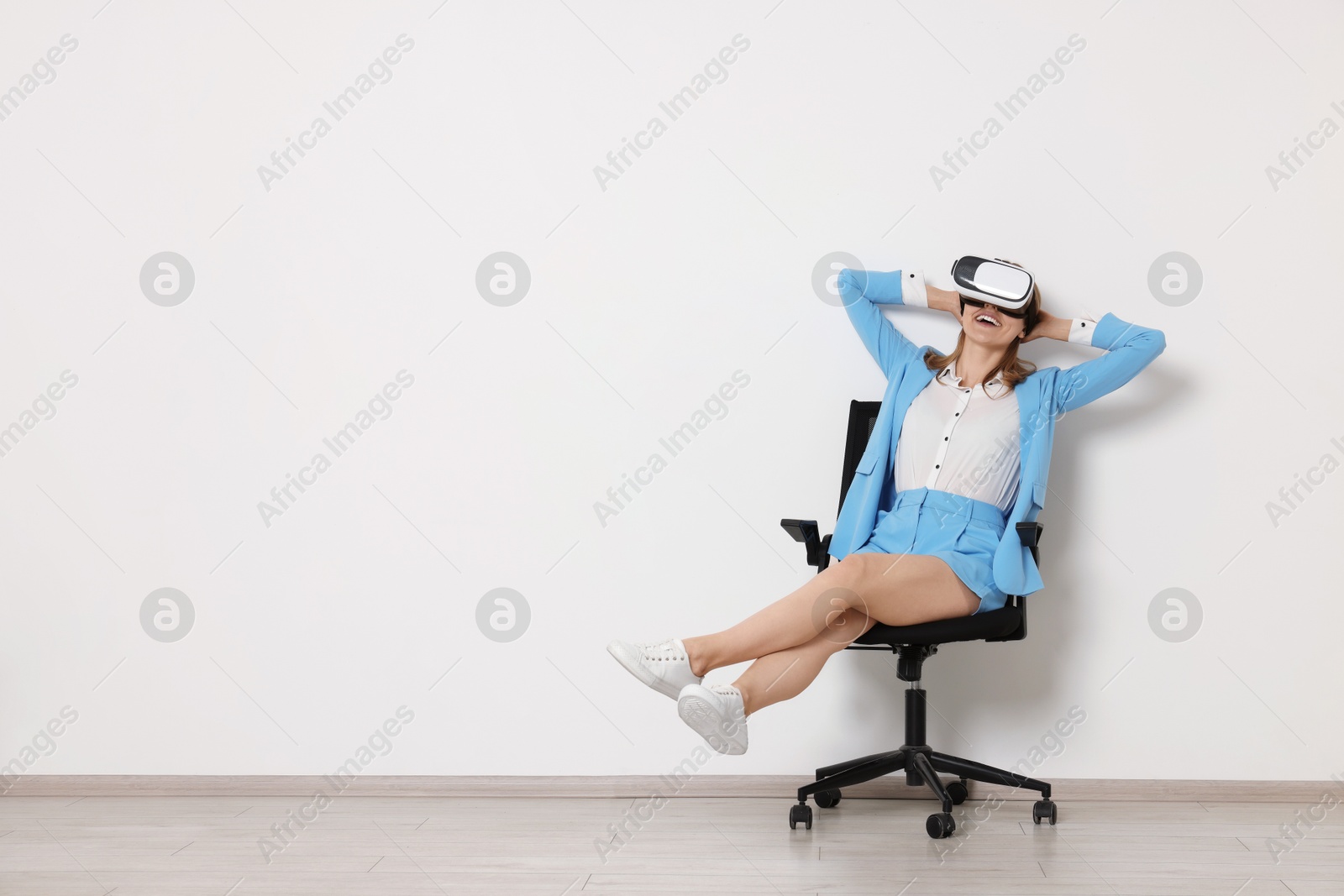 Photo of Happy woman with virtual reality headset sitting on chair indoors, space for text