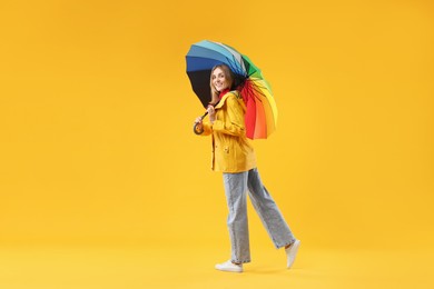 Woman with colorful umbrella on yellow background