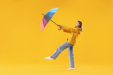 Photo of Woman with colorful umbrella on yellow background