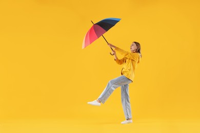 Photo of Woman with colorful umbrella on yellow background