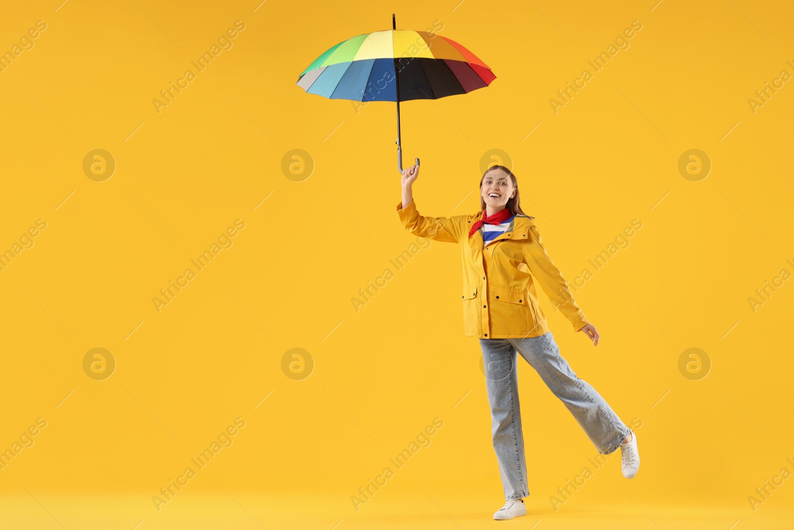 Photo of Woman with colorful umbrella on yellow background, space for text