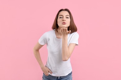 Photo of Beautiful teenage girl blowing kiss on pink background