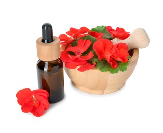 Photo of Bottle of geranium essential oil, mortar and pestle with beautiful flowers isolated on white