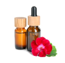 Photo of Bottles of geranium essential oil and beautiful flower isolated on white