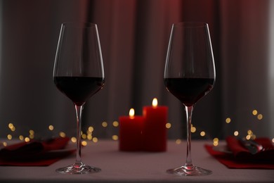 Burning candles and wine in glasses on table indoors. Bokeh effect