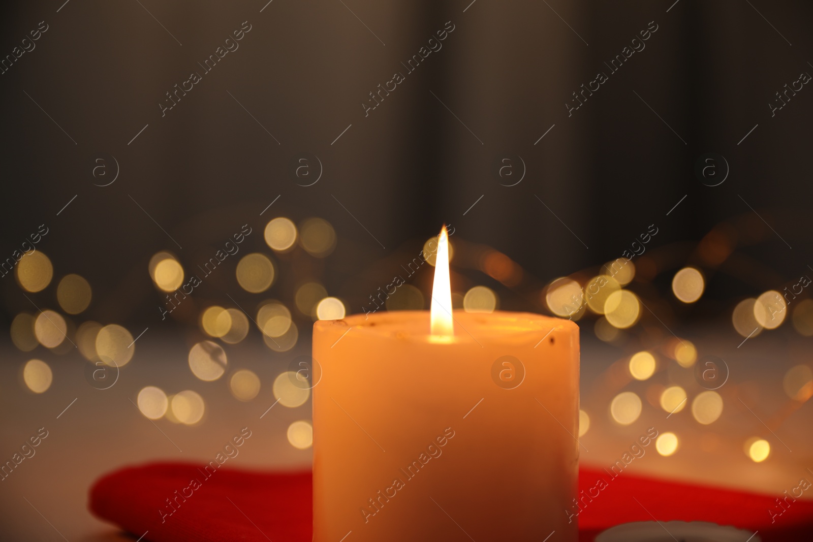 Photo of Burning candle on table indoors, closeup. Bokeh effect