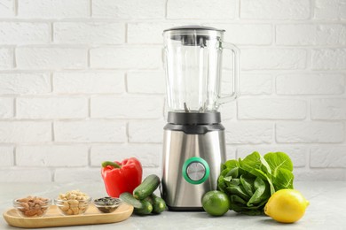 Photo of Blender and products on light table against white brick wall