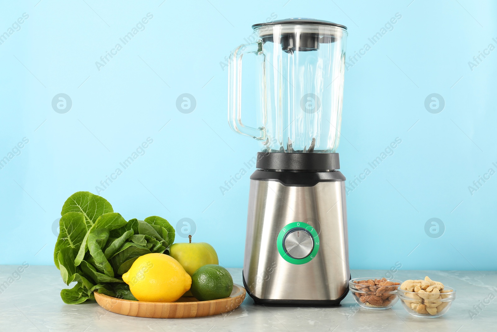 Photo of Blender and products on grey table against light blue background