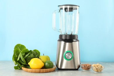 Blender and products on grey table against light blue background