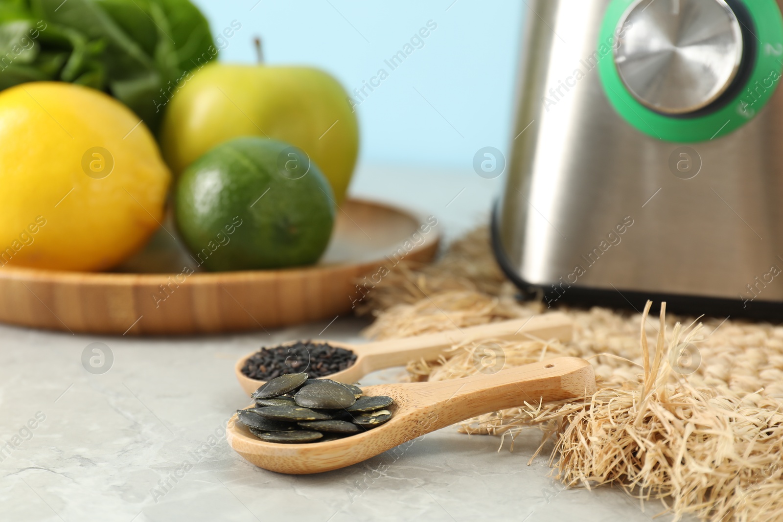 Photo of Spoons with seeds, blender and products on grey table, closeup