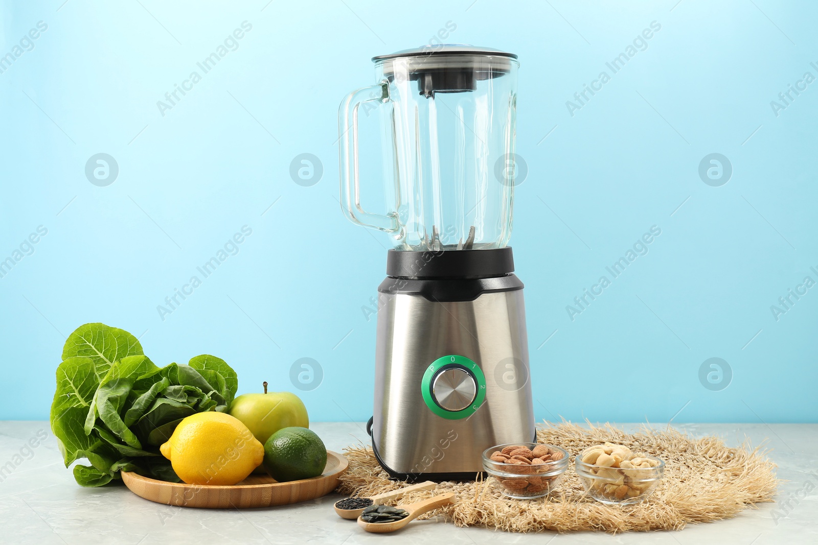 Photo of Blender and products on grey table against light blue background