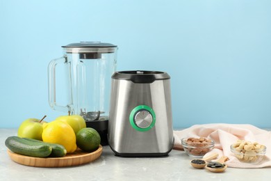 Blender and products on grey table against light blue background