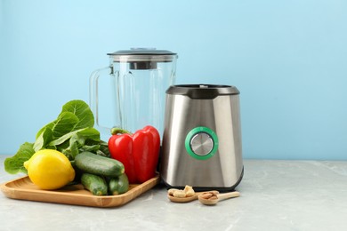 Photo of Blender and products on grey table against light blue background