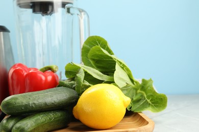 Healthy products and blender on grey table against light blue background, closeup