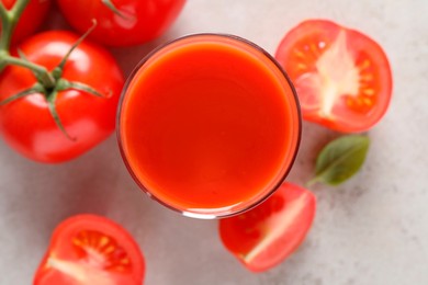 Tasty tomato juice in glass, basil and fresh vegetables on light grey table, top view