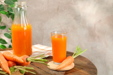 Photo of Healthy carrot juice in glass, bottle and fresh vegetables on wooden table