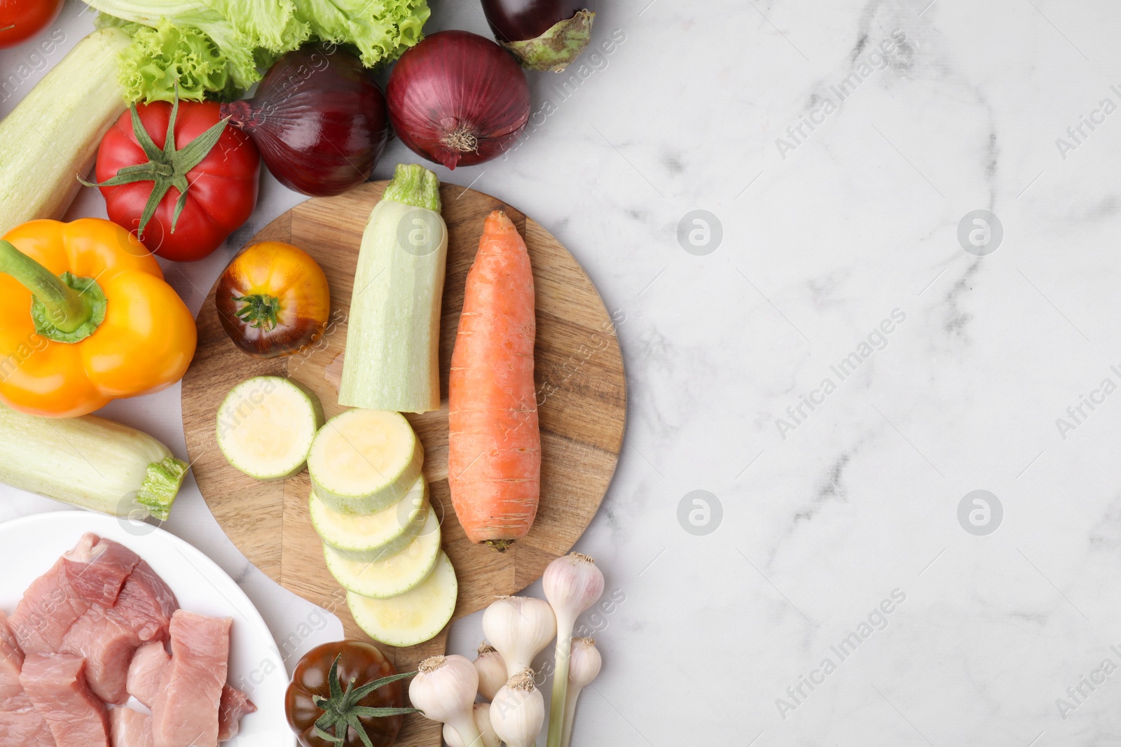 Photo of Different vegetables and raw meat for stew on white marble table, top view. Space for text