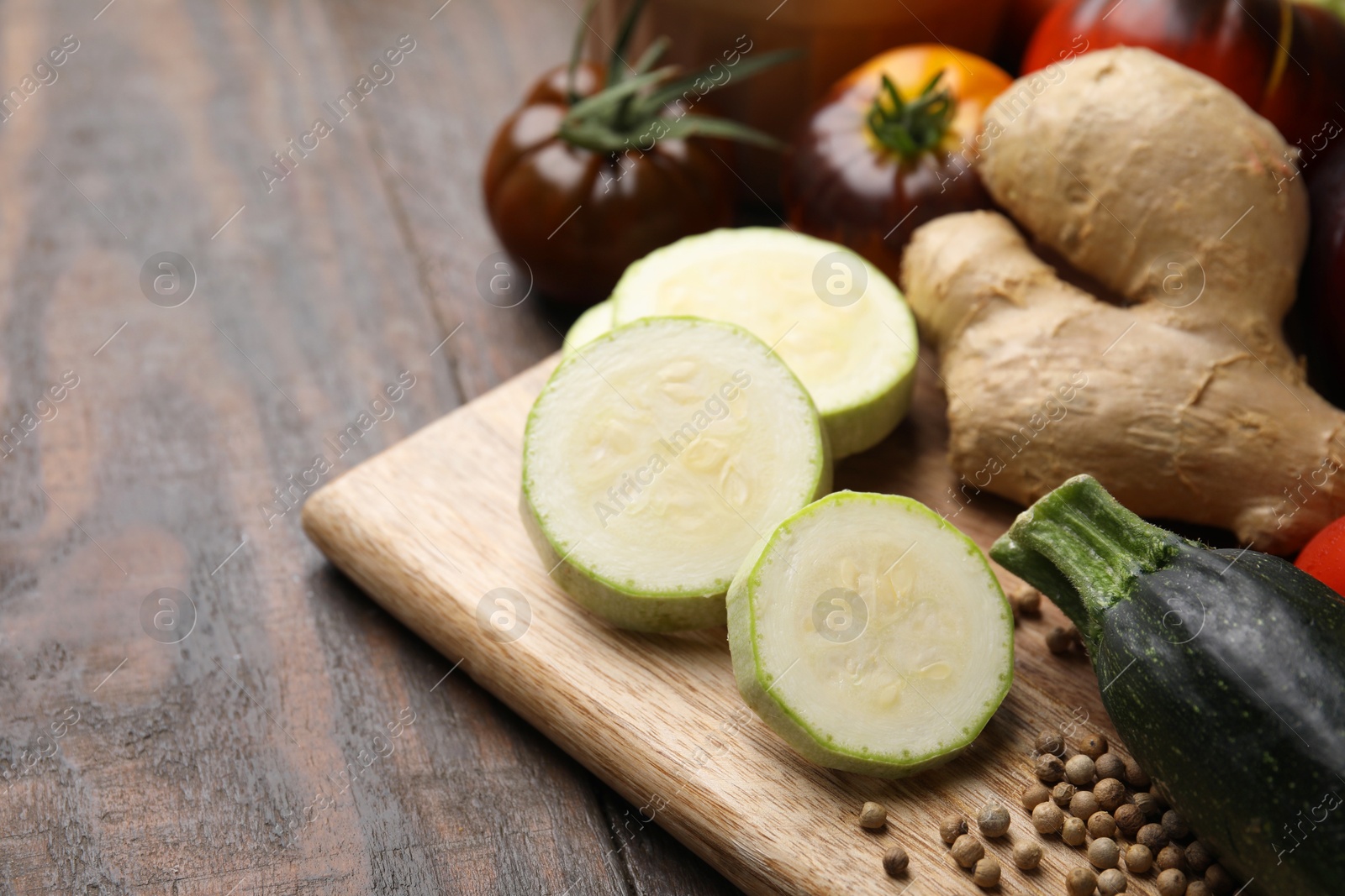 Photo of Cooking tasty stew. Fresh zucchini, ginger and tomatoes on wooden table