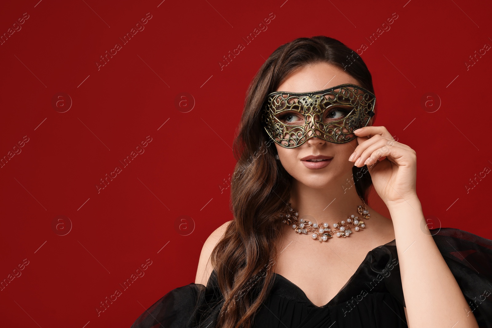 Photo of Beautiful woman wearing carnival mask on red background. Space for text