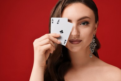 Photo of Poker game. Charming woman covering eye with playing cards on red background